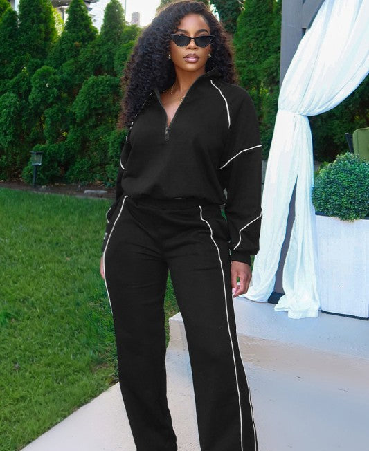 Woman wearing a black outfit with white piping in an outdoor setting